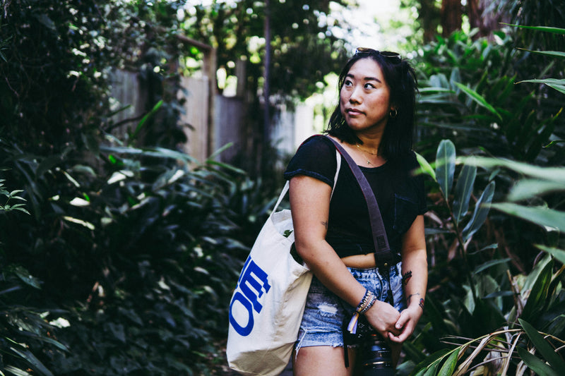 Woman carrying white canvas tote bag outdoors